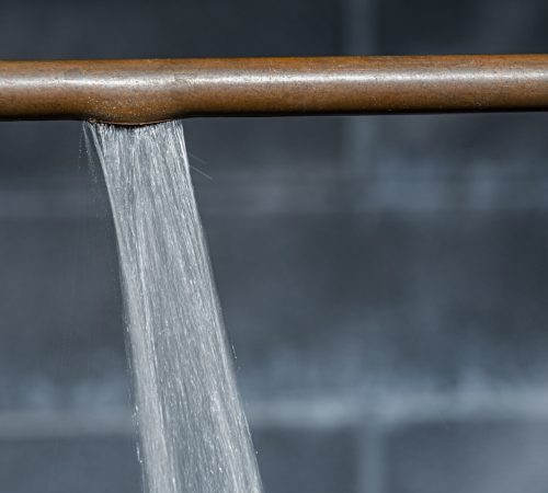 An Image Of A Brass Water Supply Line That Has Burst And Has A Spray Of Water Jetting Out.