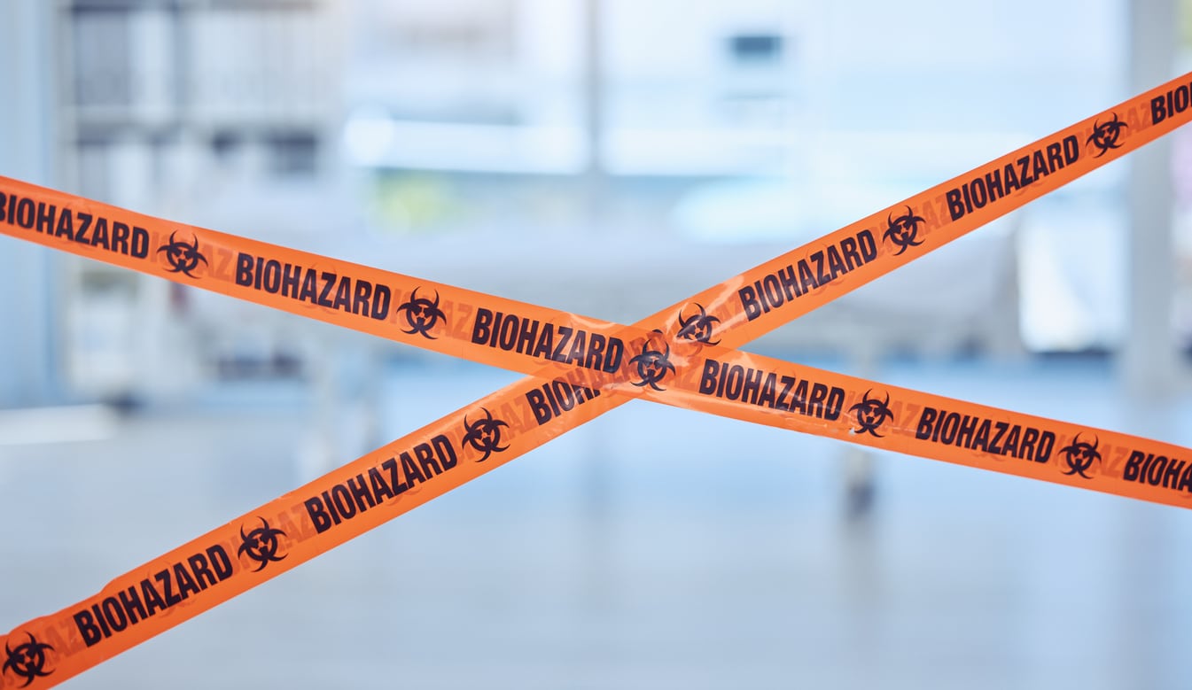 An image where everything is blurry, except for a pair of crossed plastic ‘biohazard’ barrier tapes.